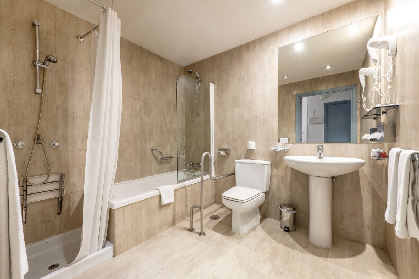 Barrierefreies Badezimmer mit bodengleicher Dusche, Haltegriffen, erhöhtem WC und unterfahrbarem Waschtisch – modern, sicher und komfortabel gestaltet.