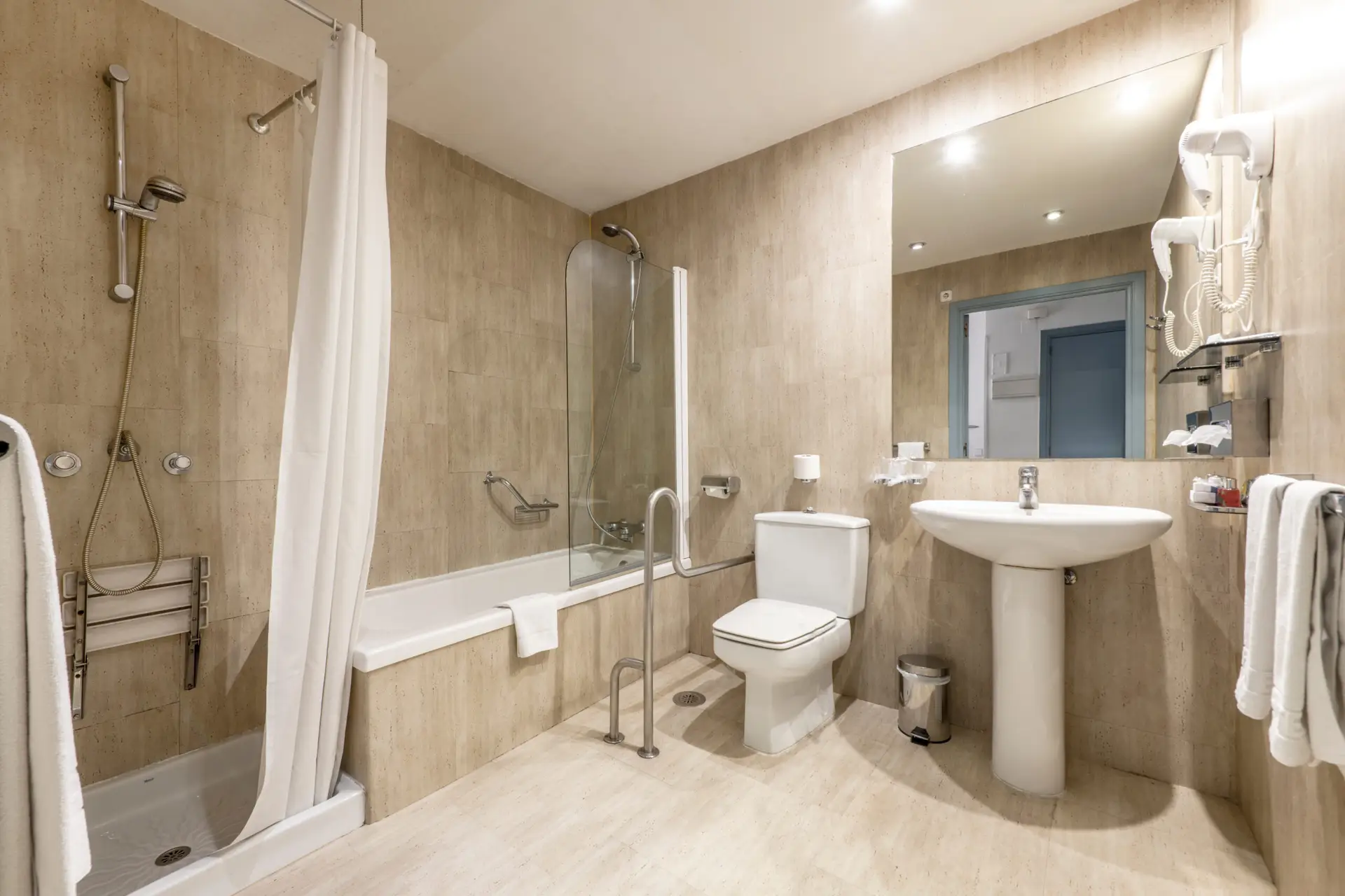 Barrierefreies Badezimmer mit bodengleicher Dusche, Haltegriffen, erhöhtem WC und unterfahrbarem Waschtisch – modern, sicher und komfortabel gestaltet.