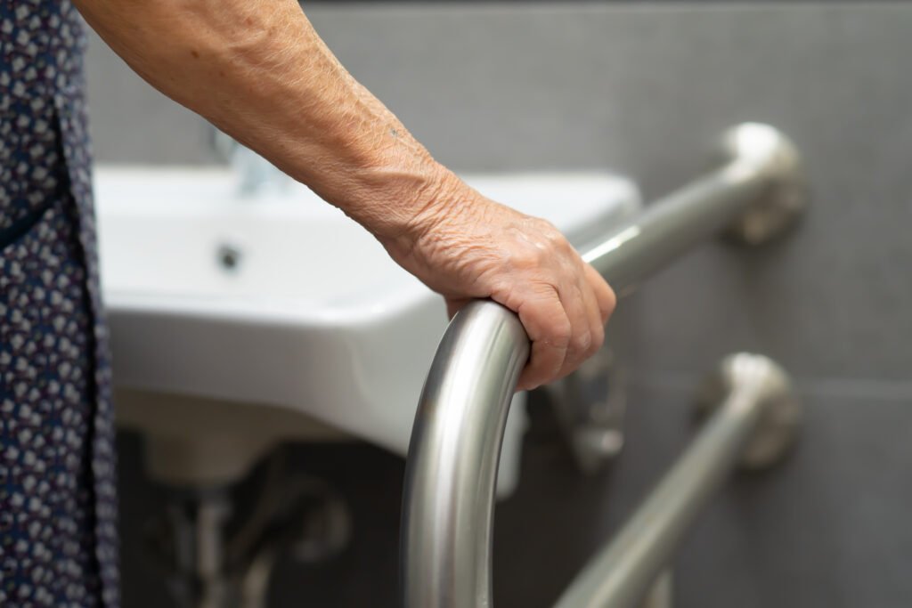 Barrierefreies WC mit erhöhter Sitzhöhe und seitlichen Stützgriffen für bequemes und sicheres Aufstehen.