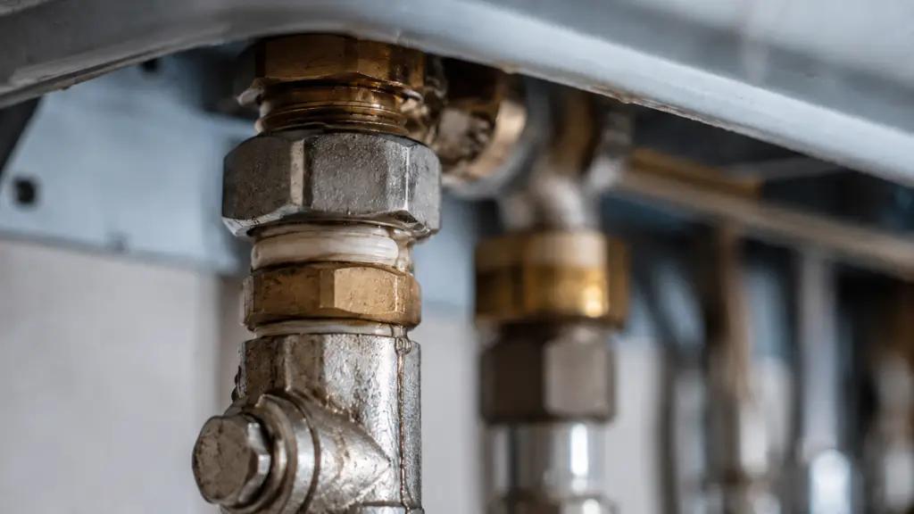 Wasser läuft an einer undichten Rohrverbindung unter einer Gastherme entlang